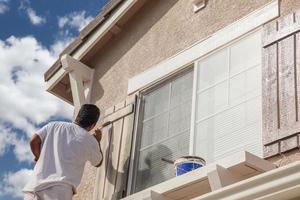 Professioneller Anstreicher, der die Zierleisten und Fensterläden eines Hauses anstreicht. foto