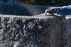 Poolbauer, der mit einer Glättkelle auf nassem Beton arbeitet foto