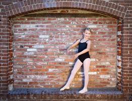 süßes kaukasisches ballerina-mädchen, das gegen eine backsteinmauer postet foto