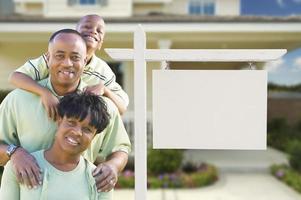 afroamerikanische familie vor leerem immobilienschild und haus foto