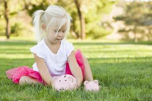 kleines Mädchen, das draußen Spaß mit ihren Sparschweinen hat foto