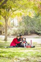 Mischlingsfamilie, die gemeinsam Weihnachtsgeschenke im Park genießt foto