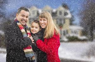 Mischlingsfamilie vor Haus im Schnee foto