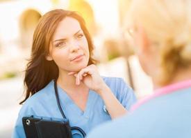 Zwei junge erwachsene professionelle Ärztinnen oder Krankenschwestern sprechen draußen. foto