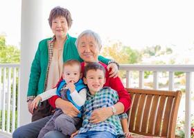 älteres erwachsenes chinesisches paar, das mit ihren enkelkindern gemischter rassen sitzt foto