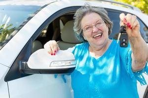 glückliche Seniorin mit neuem Auto und Schlüsseln foto