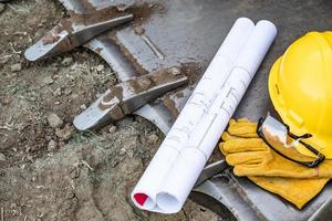 technische pläne, hardhat, handschuhe und schutzbrillen, die auf einer planierraupenschaufel ruhen, abstrakt foto