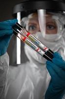 weibliche laborangestellte hält reagenzgläser mit blut, die mit der coronavirus-covid-19-krankheit gekennzeichnet sind foto