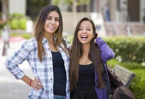 Studentinnen gemischter Rassen, die Rucksäcke auf dem Schulcampus tragen foto