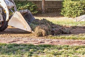 kleiner Bulldozer, der Gras vom Hof entfernt, um die Installation des Pools vorzubereiten foto