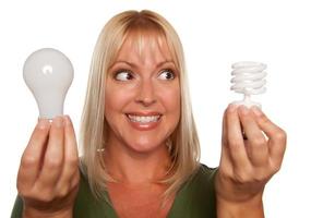 Frau hält energiesparende und normale Glühbirnen foto