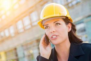 junge professionelle Auftragnehmerin mit Schutzhelm auf der Baustelle mit Handy. foto