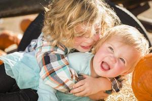 kleiner Junge spielt mit seiner kleinen Schwester im Kürbisbeet foto