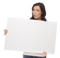 Weitäugige Mischlingsfrau, die leeres Zeichen auf Weiß hält foto