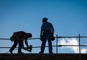 Bauarbeiter-Silhouette auf dem Dach des Gebäudes. foto