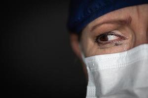 tränenreiche gestresste Ärztin oder Krankenschwester mit medizinischer Gesichtsmaske auf dunklem Hintergrund foto