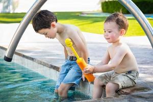 Junge chinesische und kaukasische Brüder gemischter Abstammung, die am Pool spielen foto