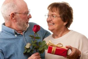 glückliches älteres paar mit geschenk und roter rose foto