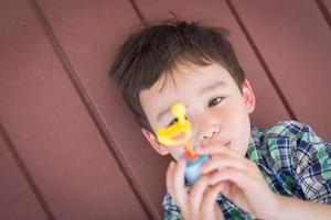 Porträt eines gemischtrassigen chinesischen und kaukasischen Jungen, der auf seiner Veranda liegt und mit Spielzeug spielt foto