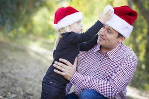 vater und tochter haben spaß beim tragen von weihnachtsmützen foto