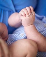 Nahaufnahme von Säuglingshänden, während sie auf dem Schoß der Mutter liegen foto