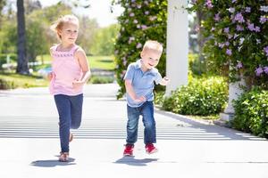 junge schwester und bruder haben spaß beim laufen im park foto