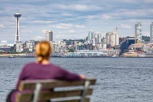 Frau sitzt auf einer Bank mit Blick auf die Skyline von Seattle, Washington foto