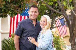 Glückliches Paar vor Häusern mit amerikanischen Flaggen foto