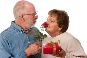 glückliches älteres paar mit geschenk und roter rose foto