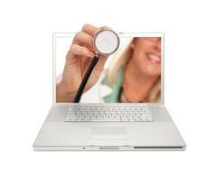 ärztin, die stethoskop durch laptop-bildschirm hält foto