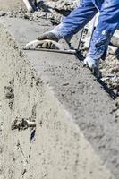 Poolbauarbeiter, der mit Holzschwimmer auf nassem Beton arbeitet foto