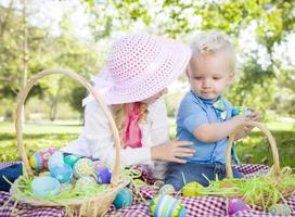 süßer junger Bruder und Schwester genießen ihre Ostereier draußen foto