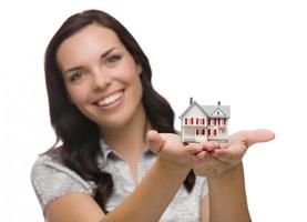 glückliche Mischlingsfrau, die kleines Haus lokalisiert auf Weiß hält foto