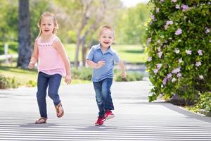 junge schwester und bruder haben spaß beim laufen im park foto