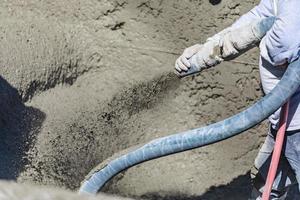 Poolbauer, der Beton, Spritzbeton oder Spritzbeton durch einen Schlauch schießt foto