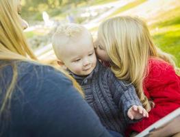 Mutter, die ihren beiden entzückenden blonden Kindern ein Buch vorliest foto