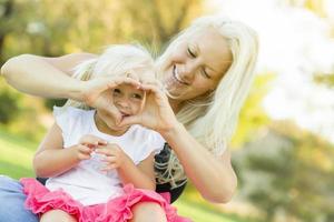 kleines Mädchen mit Mutter, die mit den Händen Herzform macht foto