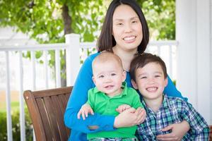 Außenporträt einer chinesischen Mutter mit ihren zwei gemischtrassigen chinesischen und kaukasischen Jungen foto
