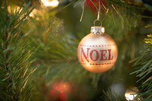 Noel geschrieben auf Weihnachtsschmuck, der am Baum hängt foto