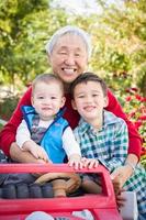 glücklicher älterer erwachsener chinesischer mann, der mit seinen enkelkindern gemischter rassen spielt foto