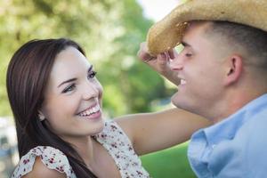 Romantisches Paar gemischter Rassen mit Cowboyhut, das im Park flirtet foto