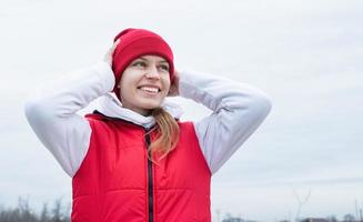 Porträt einer jungen Frau in leuchtend roter und weißer Sportkleidung im Freien foto