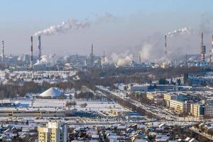 ariel Panoramablick auf die Stadt und die Wolkenkratzer mit einer riesigen Fabrik mit rauchenden Schornsteinen im Hintergrund foto