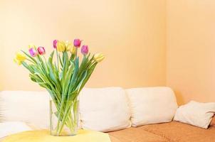 helles minimales wohnzimmer mit frühlingsblumenstrauß aus tulpen. 8. märz, geburtstag, valentinstagkonzept. foto