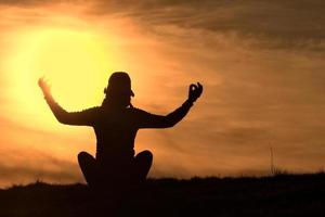 Silhouette des Mädchens, das Yoga Sonnenuntergang praktiziert foto