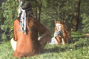 hübsche freie Hippie-Mädchen auf dem Rasen, die Fotos mit einem alten Vintage-Effekt-Foto machen