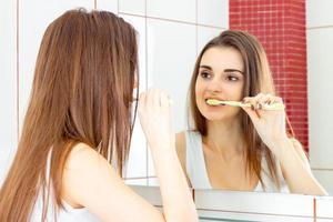 Brunettemädchen im Badezimmer, das Zähne putzt foto