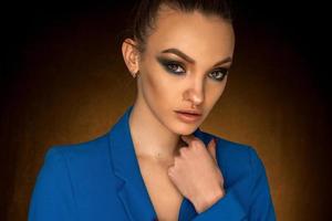 schönes junges Mädchen in blauer Jacke mit Beauty-Make-up im Studio foto