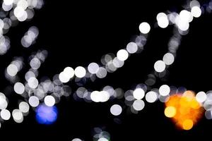 Unfokussiertes abstraktes buntes Bokeh mit roter, grüner, oranger und blauer Lampe auf schwarzem Hintergrund. defokussiert und verschwommen viele runde licht foto