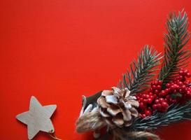 Weihnachtsdekoration. tannenzweig frisch dekoriert vor rotem farbhintergrund, draufsicht, kopierraum foto